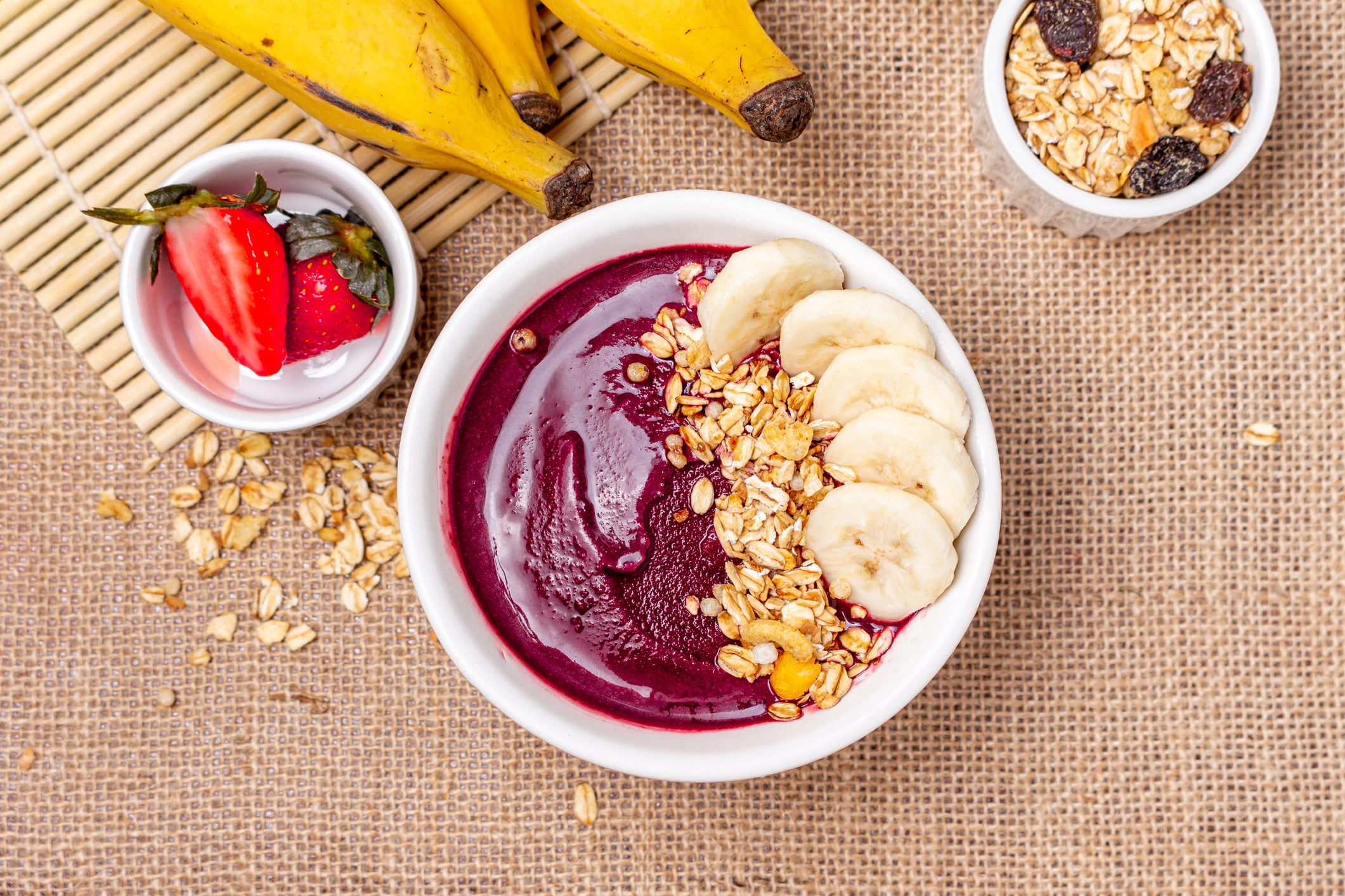 Açaí bowl topped with banana slices and granola, surrounded by fresh strawberries, bananas, and oats—ideal for a blog on top açaí bowl franchise opportunities in 2026.